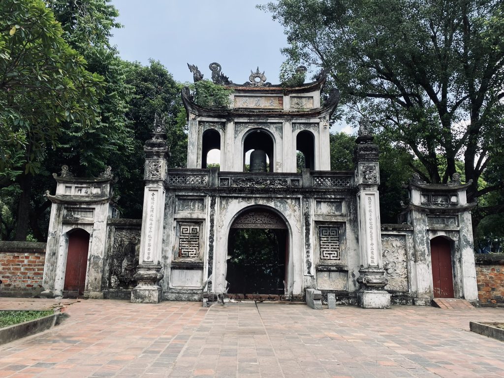 The front of a temple stands tall with trees surrounding in the heart of the Old Quarter