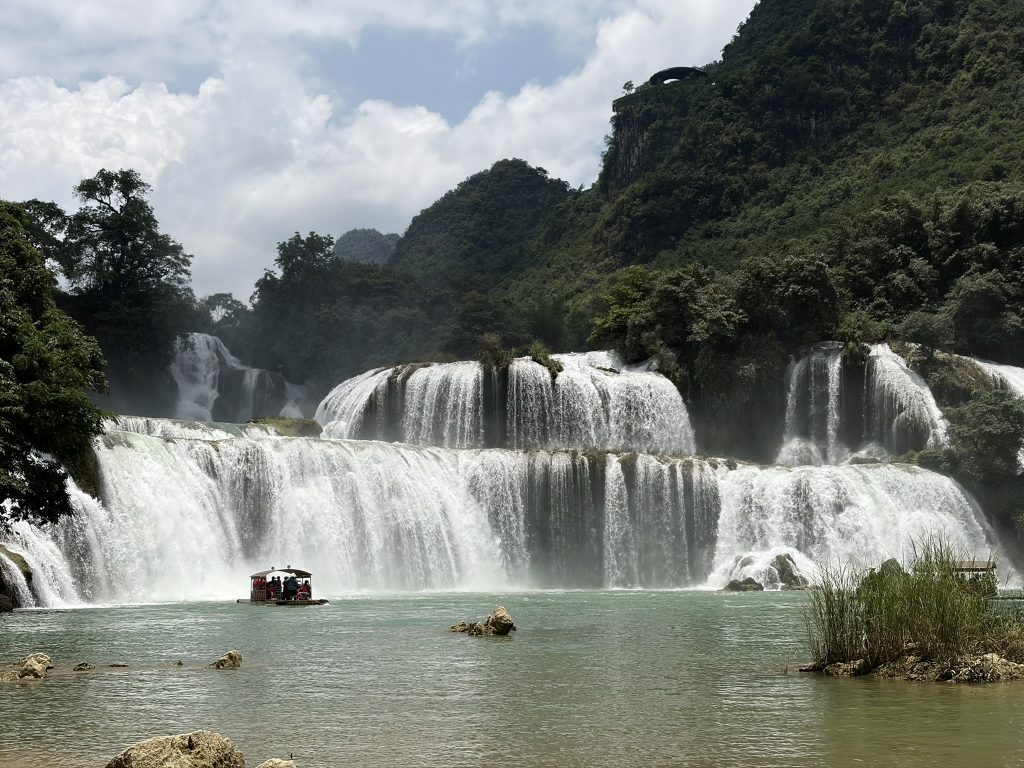 A huge waterfall separating Northern Vietnam and China tumbles into a still pond with greenery around