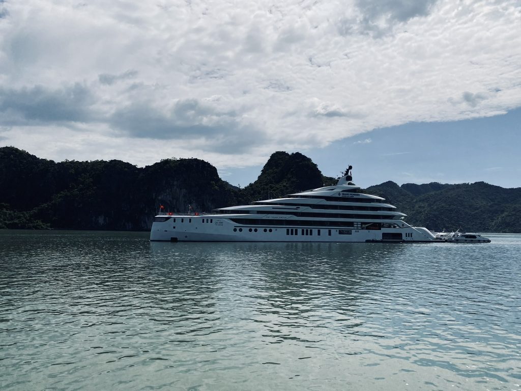 A cruise ship cuts through emerald waters with the classic Northern Vietnam karst landscape behind